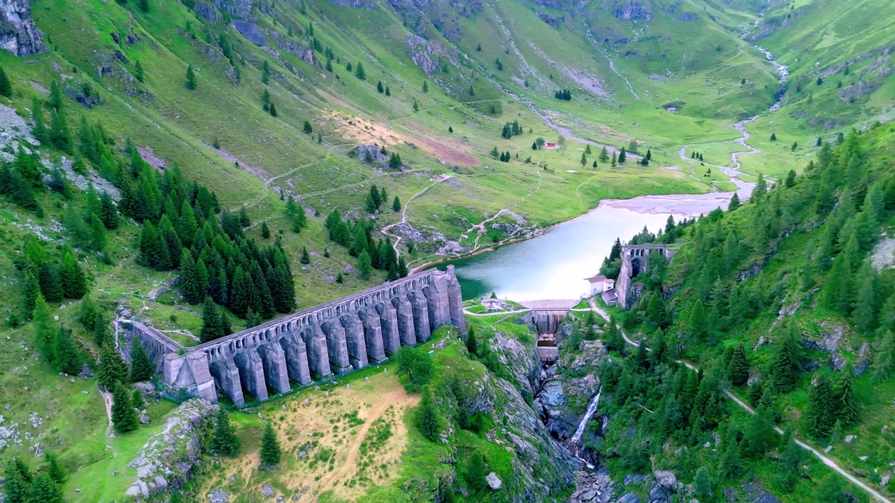Drönarbild av ruinerna från den historiska Gleno-katastrofdammen, upplysta av varmt solnedgångsljus i Val di Scalve, italienska Alperna, Italien