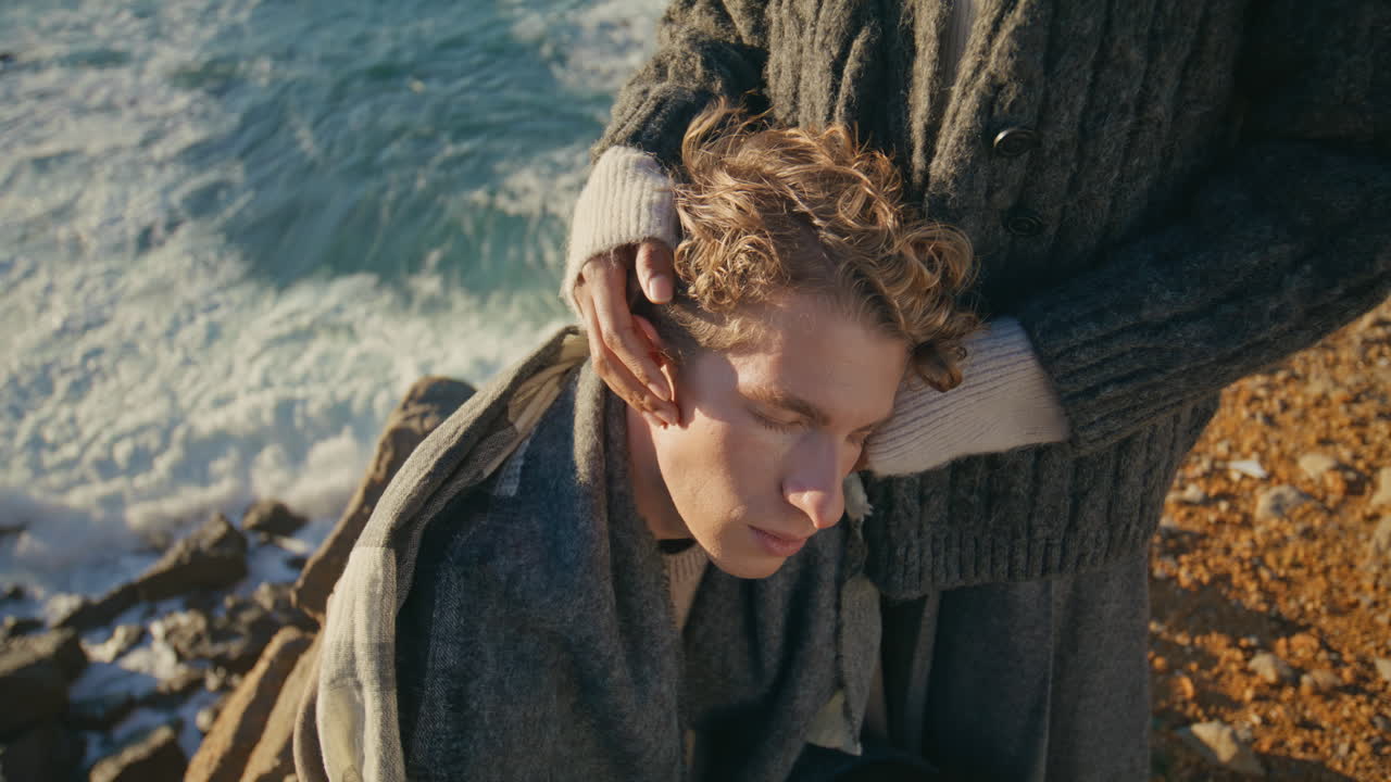 Unknown woman stroking boyfriend head on sea background closeup. Loving couple