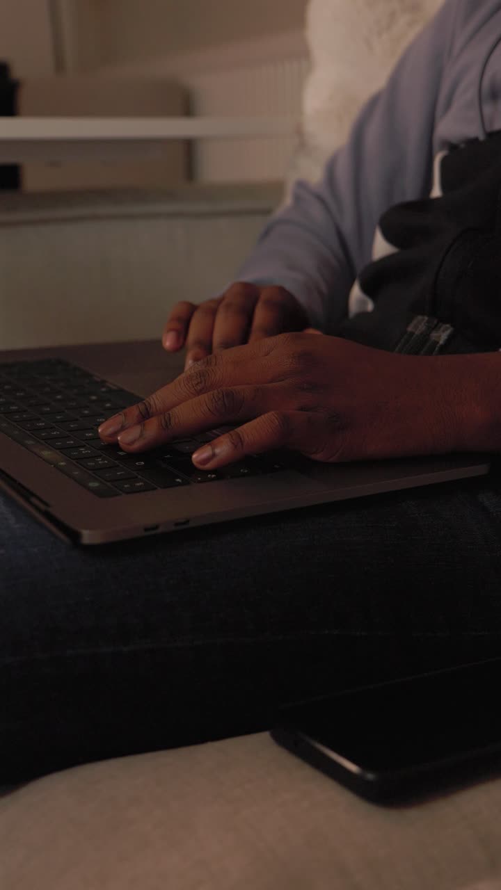 Vertical Video Of Black Male Typing On Laptop In Living Room At Home
