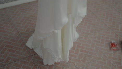 close-up of a flowing white dress touching a textured brick floor with a soft, airy feel