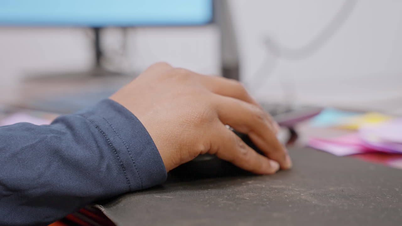 Person using computer mouse at desk in modern office workspace, shallow depth of field