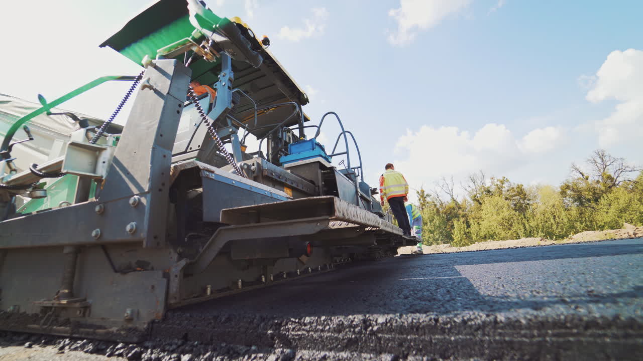 Asphalt paver machine. Worker and ashphalt paving machine during road works