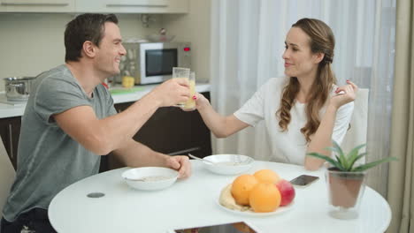 pareja feliz divirtiéndose en la cocina. hombre sonriente y mujer tintineando vasos