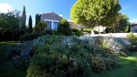 a beautifully maintained garden with the house in the backdrop at maison goult, france. the scene highlights a harmonious blend of natural beauty and charm, a serene and picturesque setting.