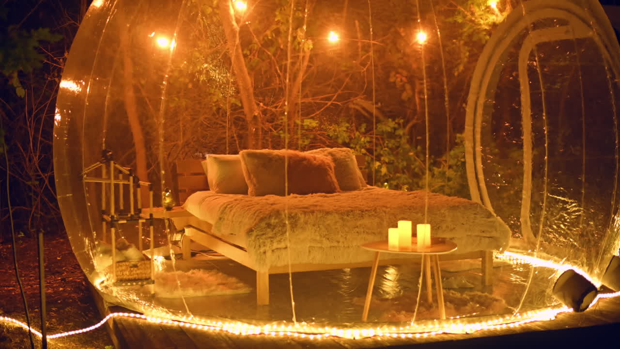 Tienda de burbujas transparente en un glamping de noche, interior con iluminación amarilla