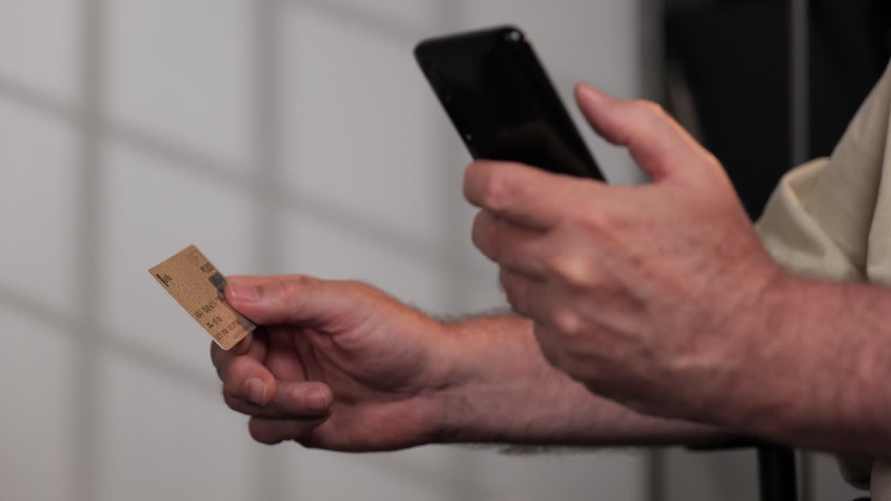 un hombre adulto hace una compra con tarjeta de crédito a través de su teléfono celular de frente