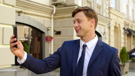 businessman having video call on mobile phone outdoors