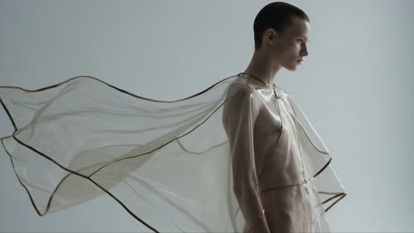 a stunning fashion portrait showcasing ethereal elegance with sheer fabric draped gracefully around a model, capturing the flow and movement of modern couture