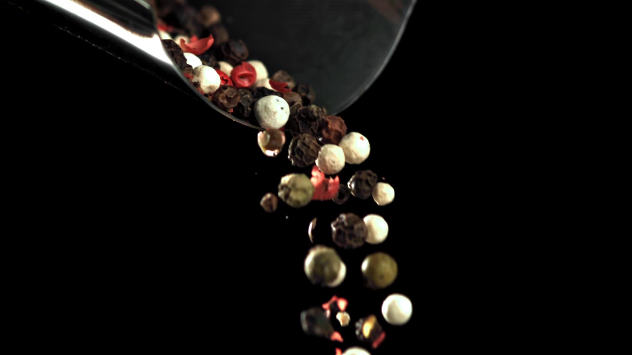 Mixed Peppercorns Falling from a Scoop in Slow Motion