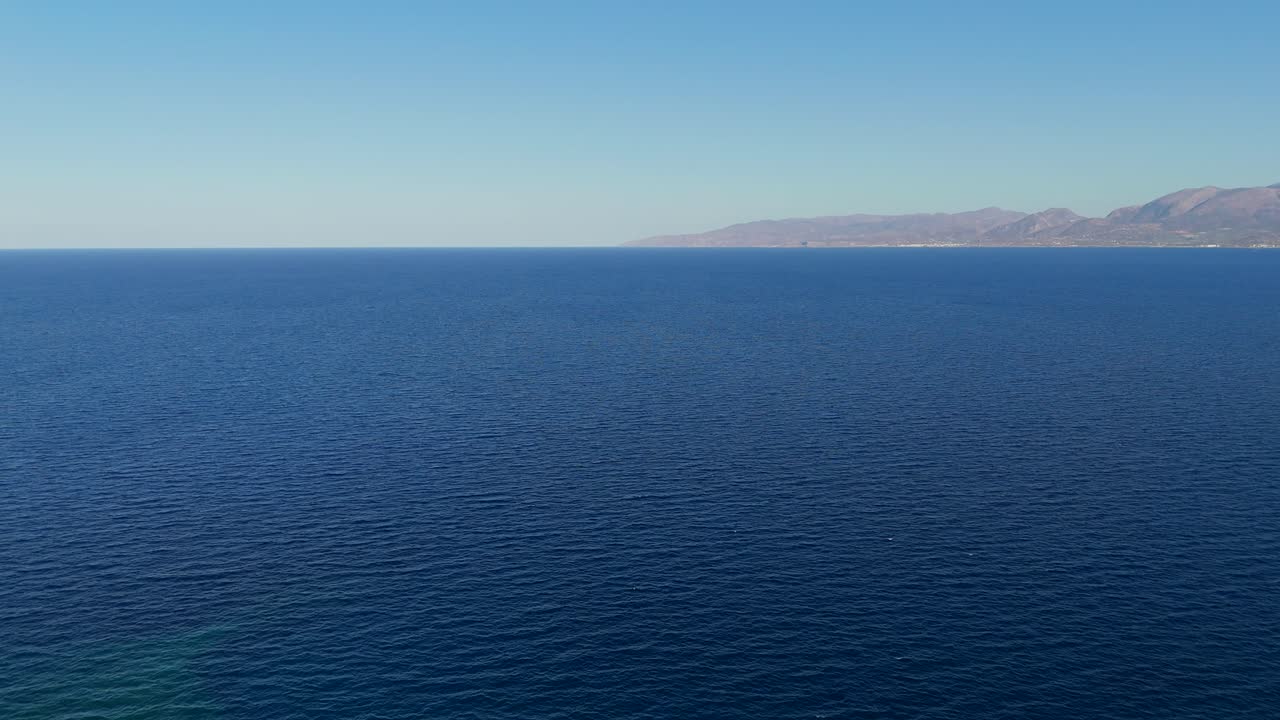 Aerial - vast blue sea with distant mountains on the horizon near Crete Greece