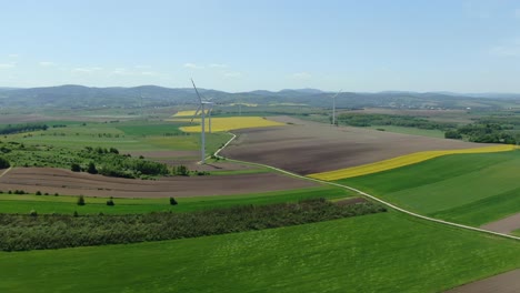 aerial panoramic reverse dolly above rolling farm fields of poland and wind turbines