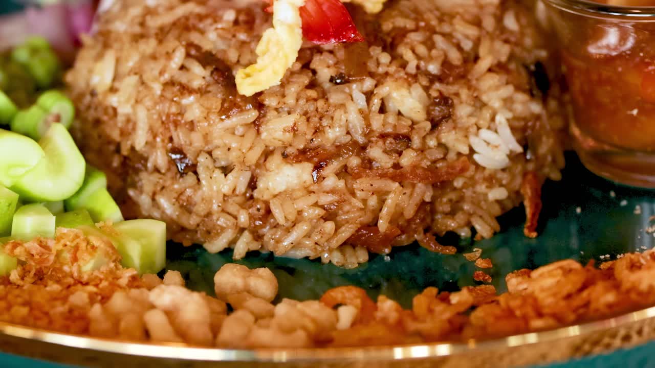 Detailed view of shrimp paste fried rice with garnishes and a side sauce.