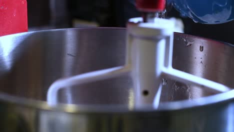 Pouring-water-into-a-stainless-mixing-bowl-while-blending-for-a-recipe