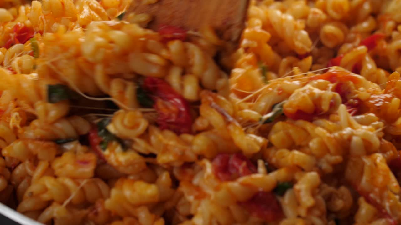 슬로우 모션으로 군침이 도는 클로즈업 샷, 나무 주걱을 사용하여 토마토 소스에 크림과 치즈 파스타를 저어 녹인 모짜렐라 치즈 스트레칭