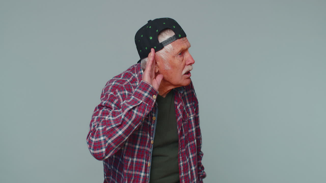 hombre tratando de oírte, mirando confundido y fruncido el ceño, manteniendo el brazo cerca de la oreja para una voz más alta, repetir