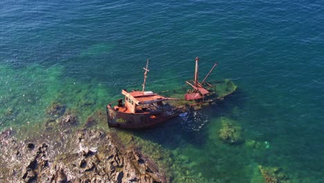 rusty shipwreck on rocky shore of blue kotor bay, aerial