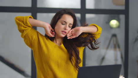 mujer de negocios cansada estirando los brazos en el interior. chica sobrecargada de trabajo bostezando cerca de la computadora portátil