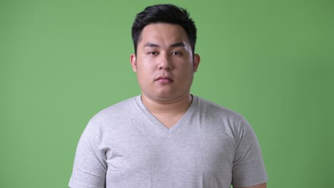 초록색 배경에 젊은 잘생긴 과체중 아시아인