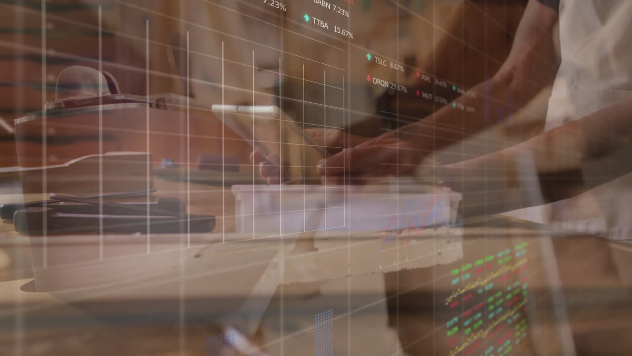 Man interacting with tablet at wooden desk, displaying animated stock market charts and tickers