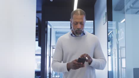 hombre de negocios que usa un teléfono inteligente en una oficina moderna