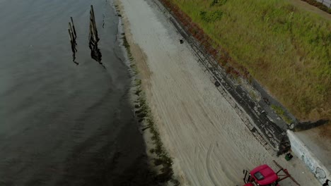 el tractor conduce por una playa vacía cerca del mar y nivela el terreno