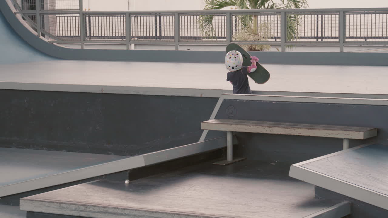 어린 어머니가 아이가 스케이트보드를 타고 있는 것을 보고 있다