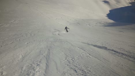 Increíble-Esquiador-Freeride-Fuera-De-Pista-Bajando-Por-Una-Profunda-Pista-De-Polvo-Con-Un-Cielo-Azul-épico-Y-Un-Fondo-De-Montaña,-Demostrando-Sentimientos-De-Diversión,-Felices-Y-Aventureras-Vacaciones-De-Esquí-De-Invierno.