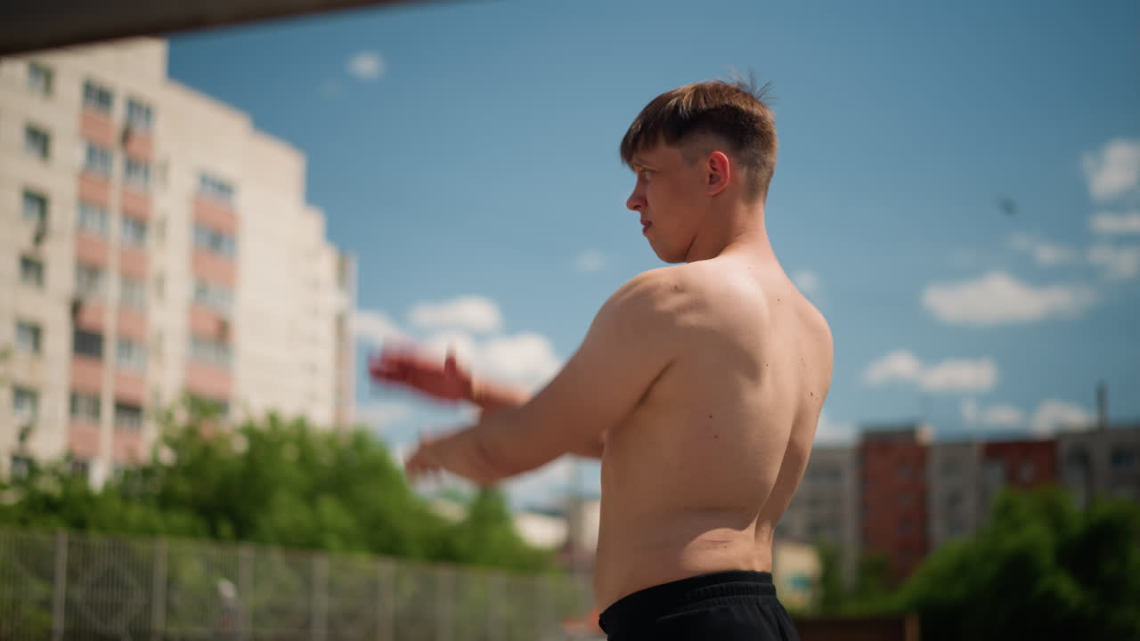 복서 옥상 운동, 상의를 탈의한 백인 복서가 도시 스카이라인을 배경으로 정확한 펀치를 연습하고, 리듬감 있는 강렬함과 도시 풍경을 담아 옥상에서 섀도 복싱 운동을 하는 집중한 남성 복서
