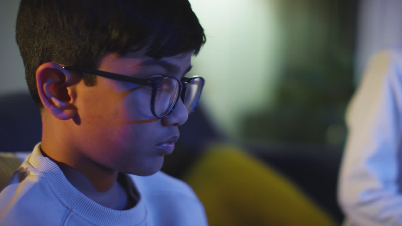 Close Up Of Two Young Boys At Home Playing With Computer Games Console On TV Holding Controllers Late At Night 10