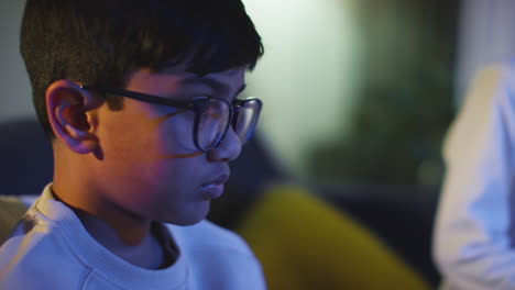 close up of two young boys at home playing with computer games console on tv holding controllers late at night 10