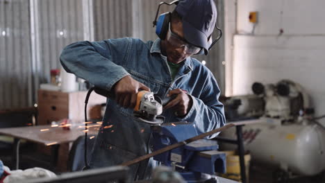 Slow-motion-young-black-male-working-angle-grinder-power-tool-in-workshop-with-sparks