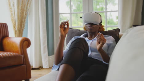 woman relaxing lying on sofa at home wearing vr headset and interacting with ar technology