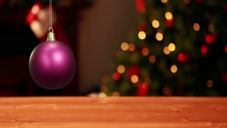 Animation-of-shiny-purple-christmas-bauble-over-defocussed-fairy-lights-flashing-on-tree