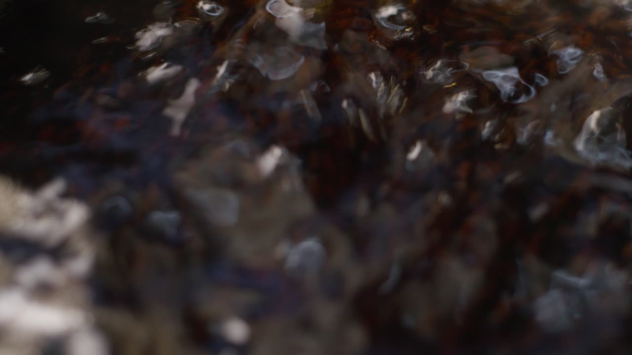 A detailed close-up, slow-motion of tea particles boiling in water with steam, preparing a hot drink
