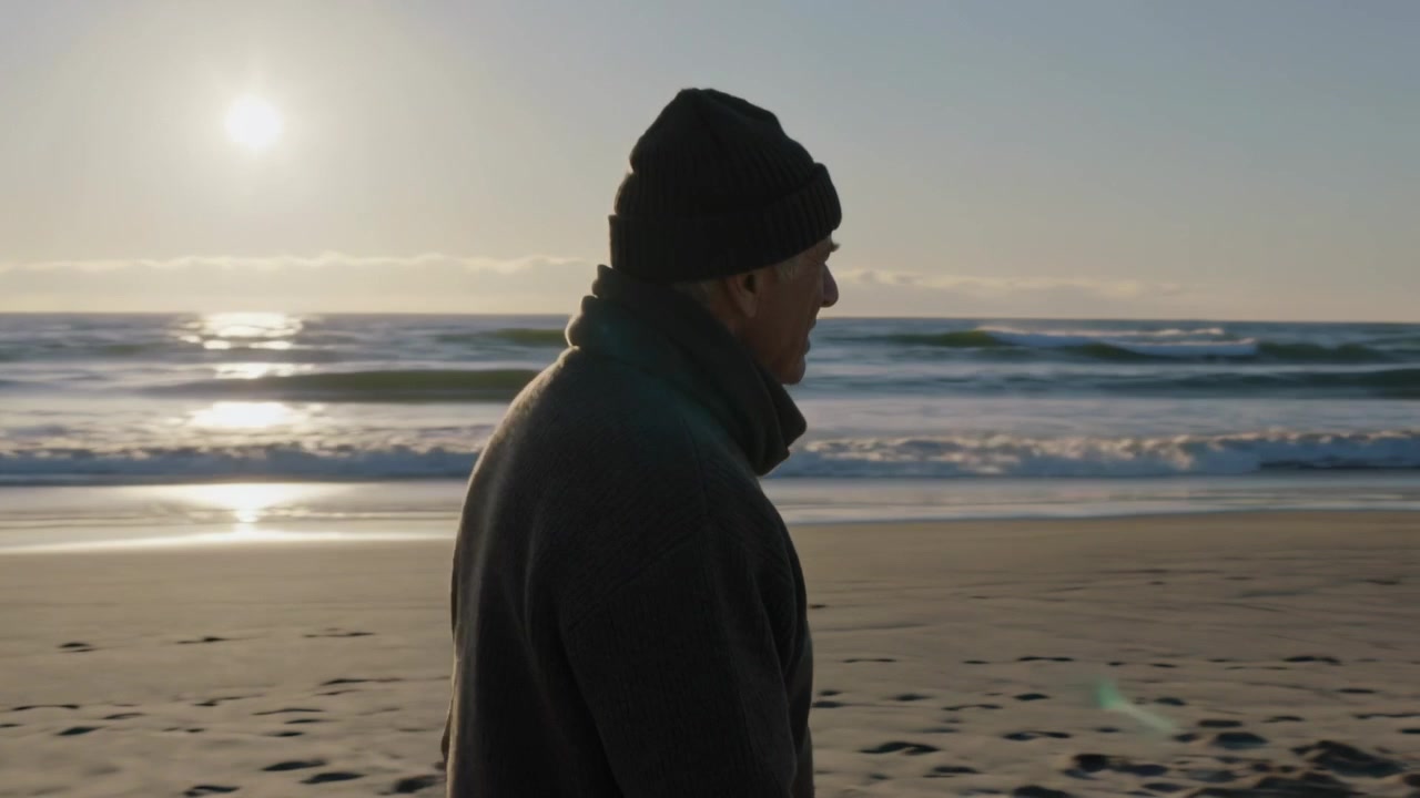 Sunset drawing senior man knit beanie scarf coat walking along wet sand leaving footprints thinking