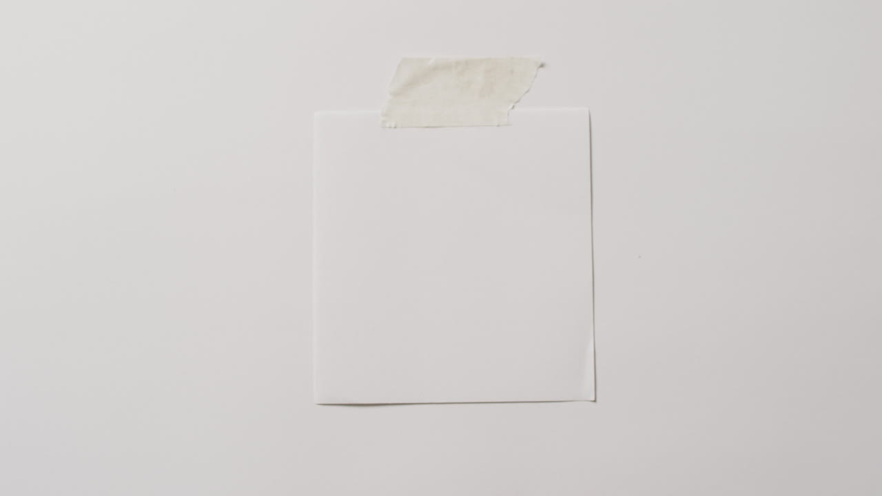 Video of close up of white memo note with copy space taped to white background