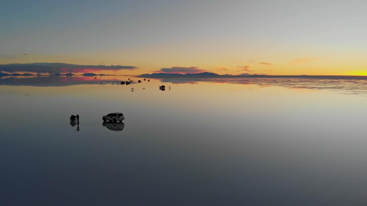 Aerial view of tourists and their vehicles on the mirrored reflection of the world's largest salt flat at dusk in Uyuni Salt Flats , Bolivia