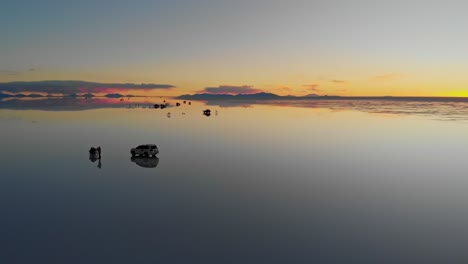 Aerial view of tourists and their vehicles on the mirrored reflection of the world&#039;s largest salt flat at dusk in Uyuni Salt Flats , Bolivia