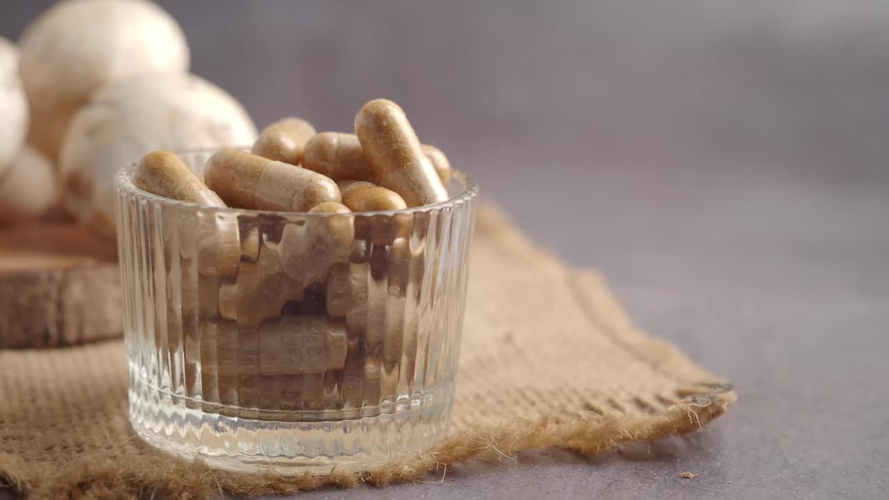 Capsule di funghi in ciotola di vetro con funghi champignon freschi