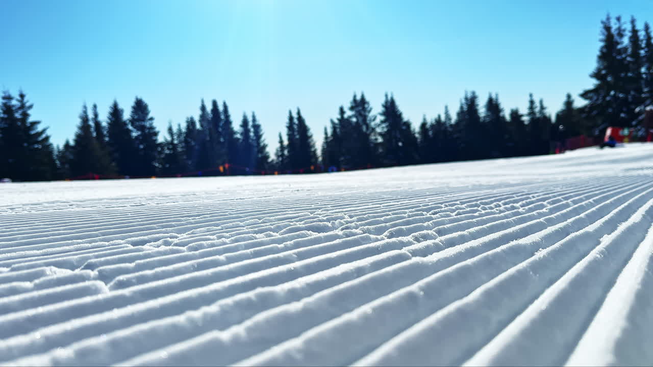 Snedækket skiløjpe med nypræparerede spor under en klar blå himmel på en solrig vinterdag i bjergene
