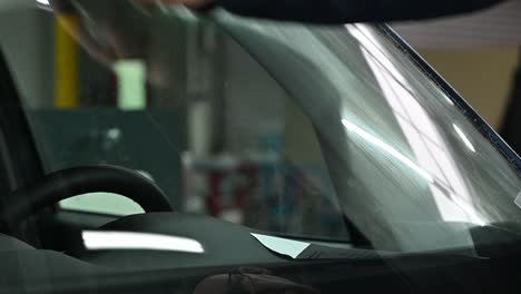 Cleaning-front-windshield-of-vehicle-with-microfiber-cloth,-close-up-view