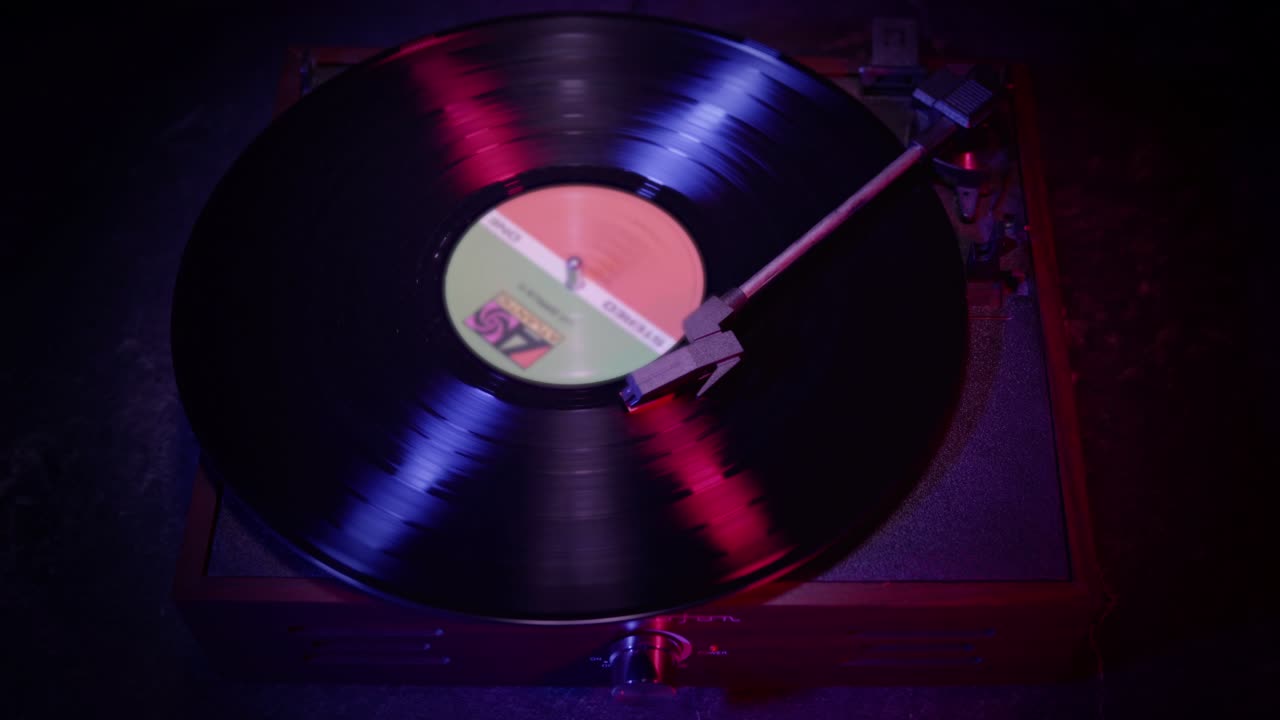 Vinile che gira su un giradischi con luci al neon rosse e blu