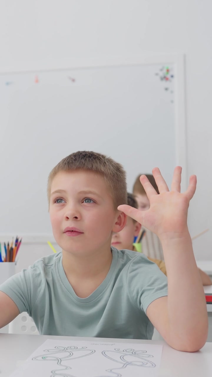 Young Boy Raising Hand and Counting in a Bright Classroom