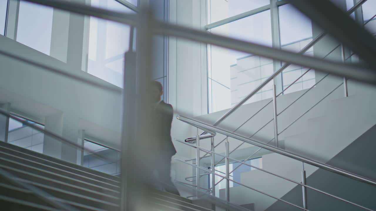 Empresário descendo as escadas de um escritório moderno. Profissional caminhando pelas escadas