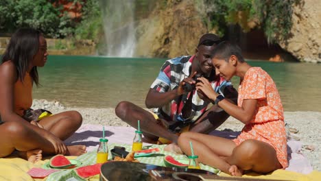 black man taking photo of women sitting on beach