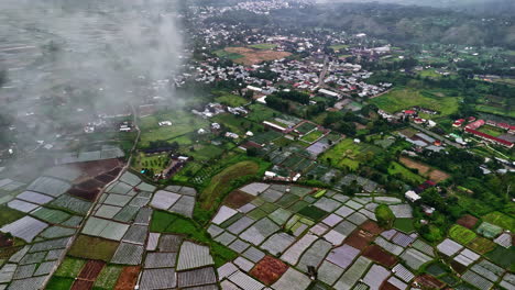 agricultural patchwork fields at bukit selong with mountain village in morning mist