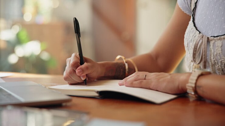 Close Up of Person's Hands Writing in a Notebook