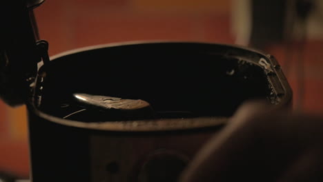 scooping coffee grounds into coffee maker and closing lid in slow-motion