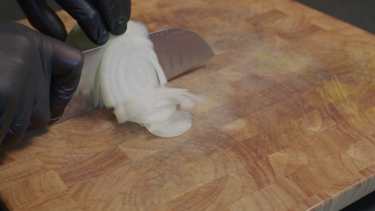 An onion is skillfully sliced on a cutting board, showcasing fundamental kitchen prep work