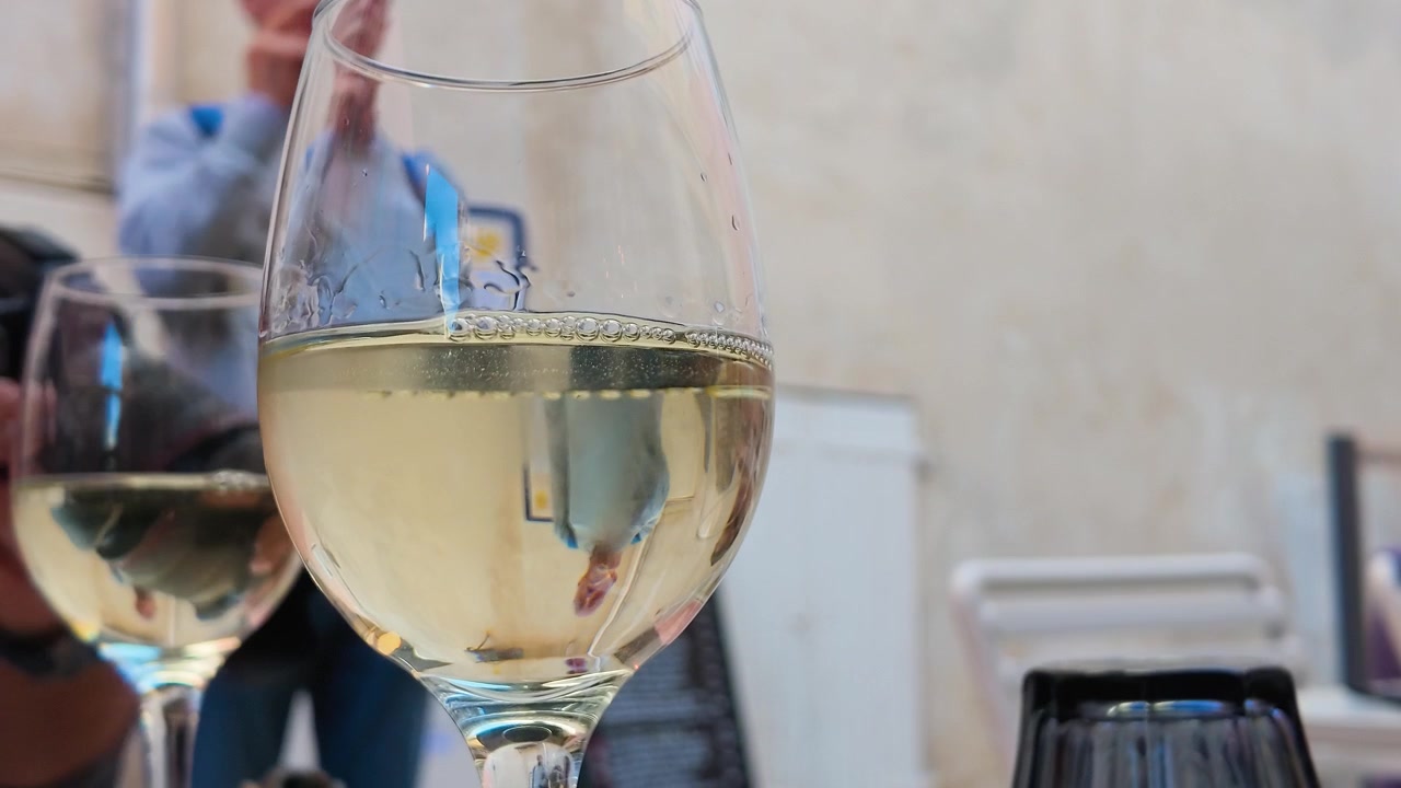 Statische Nahaufnahme von Weißwein in einem Glas in einem französischen Straßencafé.